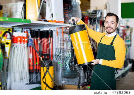Seller displaying various items in garden equipment shop 47892063