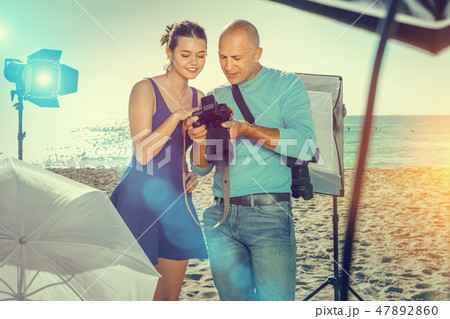Photographer and model discussing picture on camera display duri 47892860