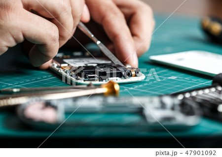 Electronics repair service. Technician disassembling smartphone for inspecting 47901092