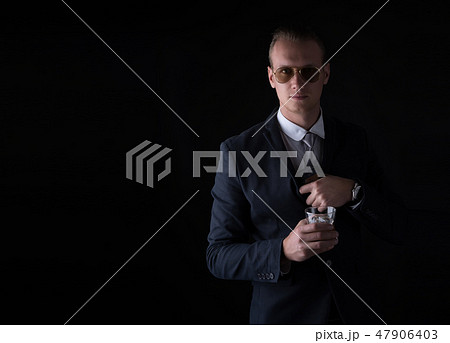 Portrait of handsome man in a suit hiding gun Portrait of handsome man in a suit hiding gun 47906403
