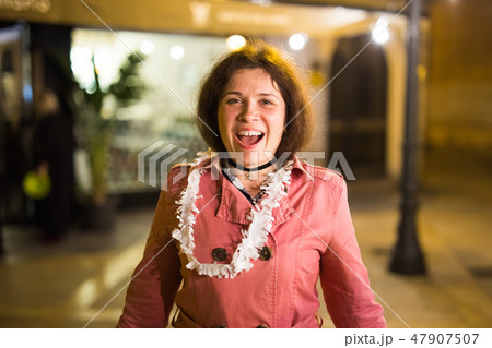 Night street portrait of smiling beautiful young woman after party and looking at camera Night street portrait of smiling beautiful young woman after party and looking at camera 47907507