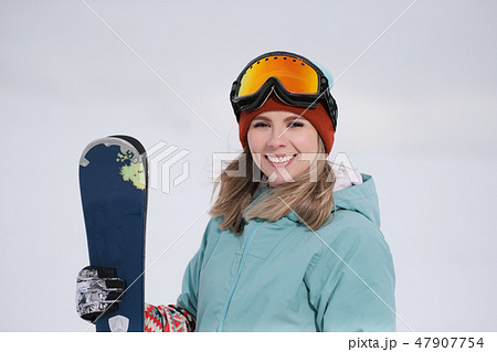 A beautiful young chew in an extreme sports suit, a hat and a helmet with a mask on the winter slope A beautiful young chew in an extreme sports suit, a hat and a helmet with a mask on the winter slope 47907754
