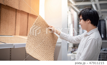Asian man shopper choosing carpet in store 47911215