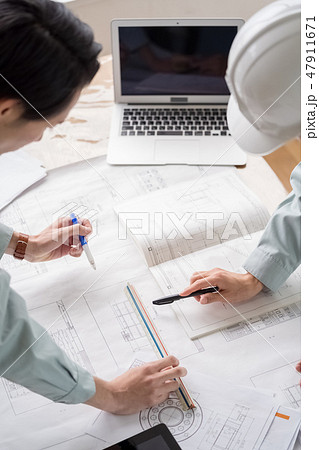 現場事務所の定例会議で図面納まりを確認し仕上げの指示をする設計事務所の一級建築士工事監理者 47911671