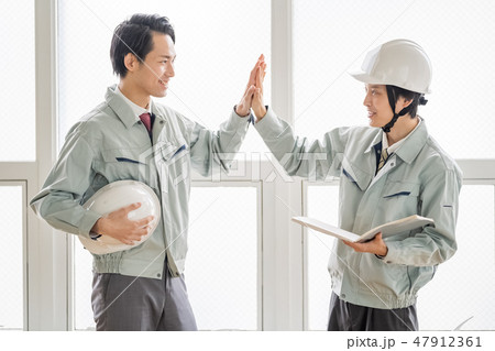 建築確認申請の主事検査を問題なく終えハイタッチで部下を労う先輩上司現場指導新人教育 47912361
