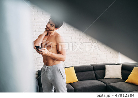 Man Working Out At Home With App On Mobile Phone 47912384