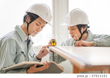 定期点検で建築確認申請副本の図面と現場寸法を測定確認するヘルメットの男性検査員二人建築士技術者 47913191