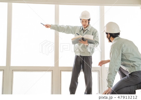 安パトで建築確認申請副本の図面と現場寸法を指差し測定確認するヘルメットの男性検査員二人建築士技術者 47913212