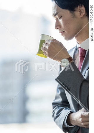 休憩時間に窓際でコーヒーを飲み仕事疲れを癒す男性ビジネスマンの渋い横顔 47914040