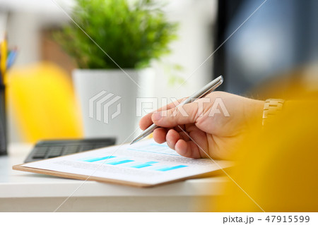 Male arm hold silver pen examining stats graphic Male arm hold silver pen examining stats graphic 47915599