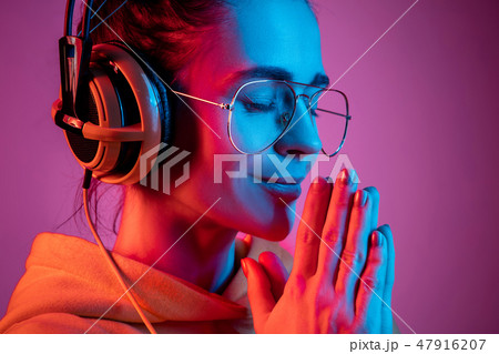 Fashion pretty woman with headphones listening to music over neon background 47916207