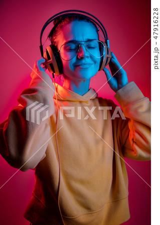 Fashion pretty woman with headphones listening to music over neon background Fashion pretty woman with headphones listening to music over neon background 47916228