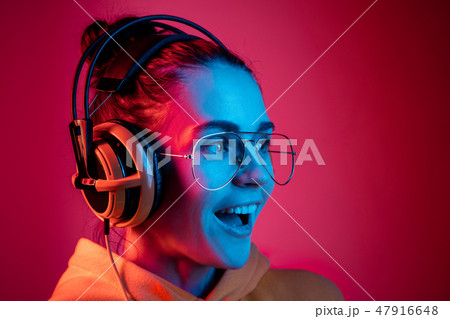 Fashion pretty woman with headphones listening to music over neon background Fashion pretty woman with headphones listening to music over neon background 47916648