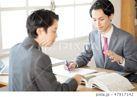 お客様へ契約前に図面を提示し重要事項説明を行う設計事務所の若い一級建築士男性ビジネスマン 47917142