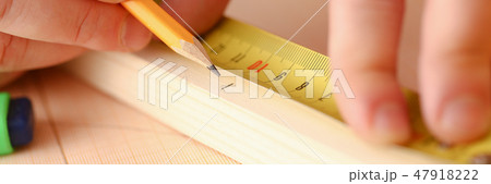 Arms of worker measuring wooden bar 47918222