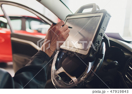 car mechanic maintains a vehicle with the help of a diagnostic computer - modern technology in the 47919843