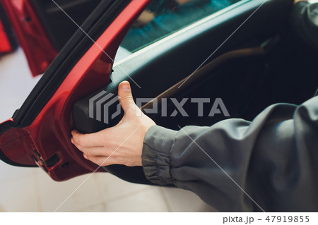 Mechanic installing car central door lock motor. Mechanic installing car central door lock motor. 47919855