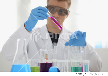 A male chemist holds test tube of glass 47922572