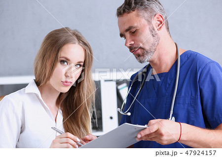 Handsome mature doctor offer pad to sign with silver pen Handsome mature doctor offer pad to sign with silver pen 47924157