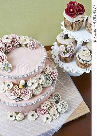 ピンクのフラワーデコレーションケーキとカップケーキの写真素材