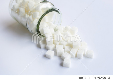 Glass bottle of sugar cubes on white. 47925018