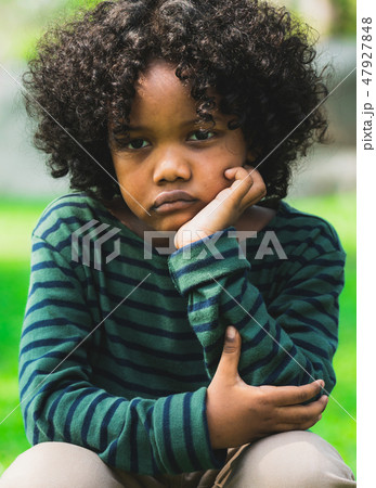 Unhappy little african american kid in the park. Unhappy little african american kid in the park. 47927848