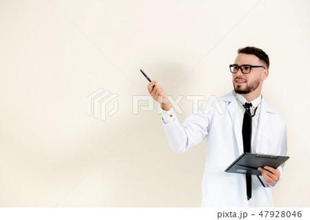 Male doctor points pen at empty wall copy space. Male doctor points pen at empty wall copy space. 47928046