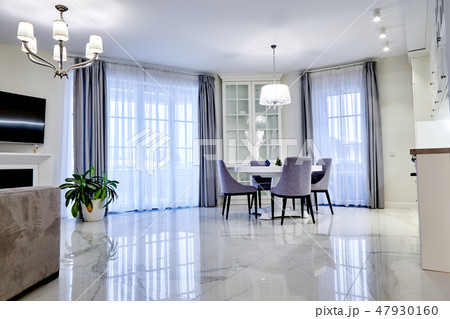 Minimalistic interior of living room in light tone with marble flooring, large windows and a table 47930160