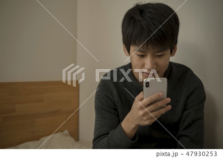 ベッドでスマートフォンを使う男の子 寝不足 中学生 高校生 ベッドでスマートフォンを使う男の子 寝不足 中学生 高校生 47930253