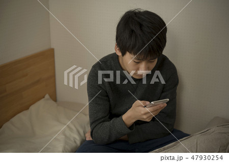 ベッドでスマートフォンを使う男の子 寝不足 中学生 高校生 ベッドでスマートフォンを使う男の子 寝不足 中学生 高校生 47930254