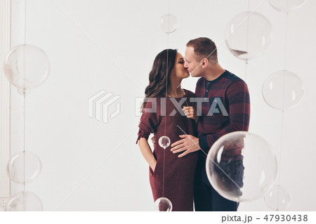 Family portrait: the husband embraces the pregnant wife on a white background. pregnant couple in 47930438