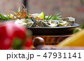 Oysters baked with cheese and herbs on plate at vegetable background. Seafood composition 47931141