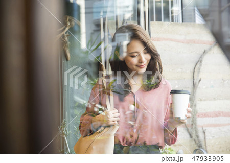 コーヒーをテイクアウトして店を出る女性 コーヒーをテイクアウトして店を出る女性 47933905