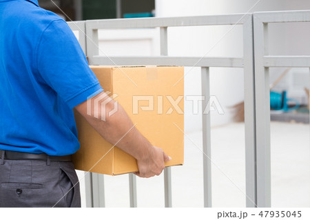 Delivery man holding a parcel and waiting recieved 47935045