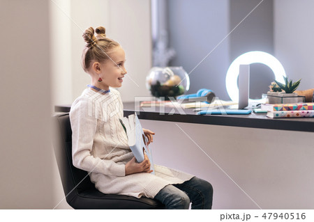 Cute blue-eyed long-haired girl with bright earrings looking amused 47940516
