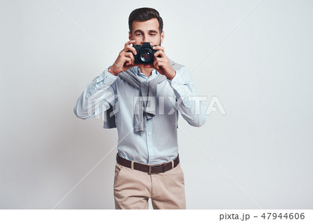 Smile! Close up photo of handsome male photographer in casual clothes who is taking photos with 47944606