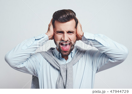 Bla bla bla! Young handsome man is stressed by noise, closing ears with both hands while standing on 47944729