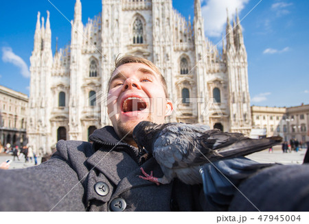 Travel, holidays and winter vacations concept - Happy man take selfie photo with funny pigeons in 47945004