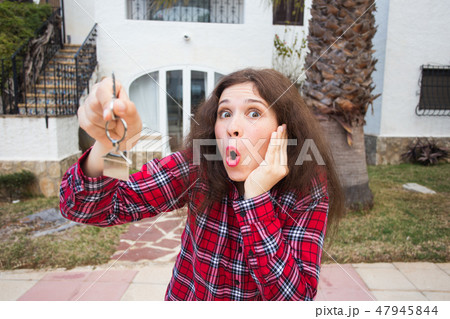 New home, house, property and tenant - Young funny woman holding key in front of her new home after 47945844