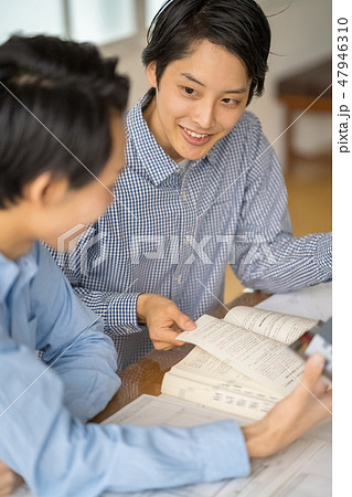 信頼のある先輩から一級建築士の試験勉強を教えてもらい嬉しそうに楽しく勉強する若い男性会社員 47946310