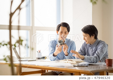 信頼のおける先輩から一級建築士の試験勉強を教えてもらい嬉しそうに楽しく勉強する若い男性会社員 47946320