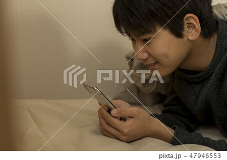 ベッドでスマートフォンを使う男の子 寝不足 中学生 高校生 ベッドでスマートフォンを使う男の子 寝不足 中学生 高校生 47946553