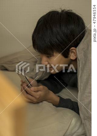 ベッドでスマートフォンを使う男の子 寝不足 中学生 高校生 ベッドでスマートフォンを使う男の子 寝不足 中学生 高校生 47946554