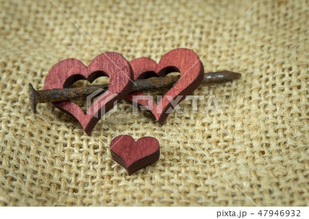 Wooden hearts with rusted nail on jute surface Wooden hearts with rusted nail on jute surface 47946932