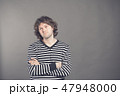 Studio shot of pensive young European male with voluminous hair posing at blank wall, keeping arms 47948000