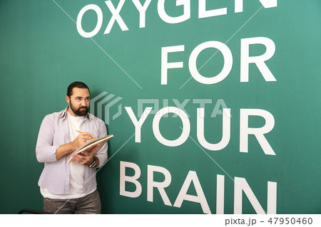 Dark-haired bearded man in a white t-shirt making notes Dark-haired bearded man in a white t-shirt making notes 47950460