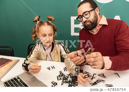 Dark-haired bearded teacher in eyewear showing new words to his pupil 47950754