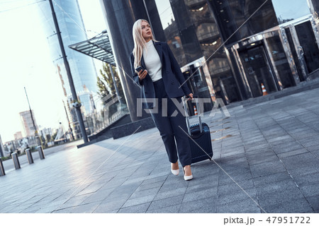 Full length portrait of a smiling successful businesswoman pulling suitcase 47951722