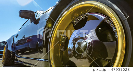 Refkective black car with gold and black tire rim 47955028