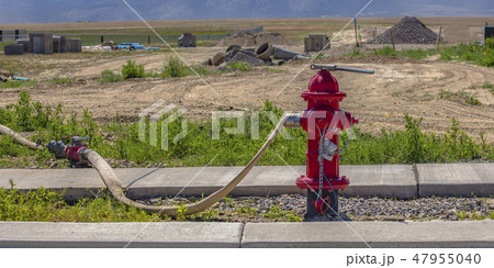 Red fire hydrant with connected hose and wrench Red fire hydrant with connected hose and wrench 47955040